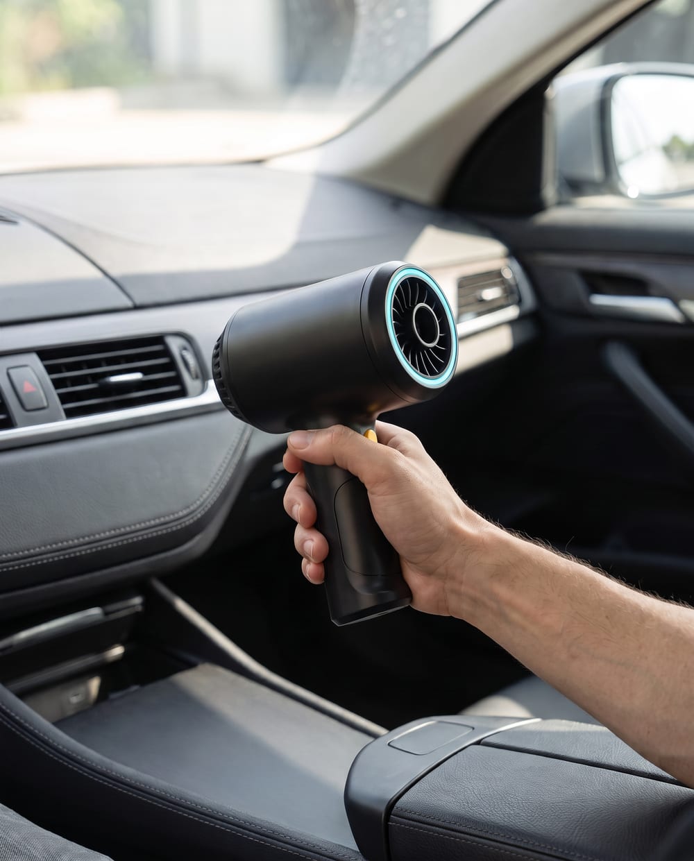 VORTEX Mini Turbo Fan usado con una mano dentro de un coche, limpiando el salpicadero